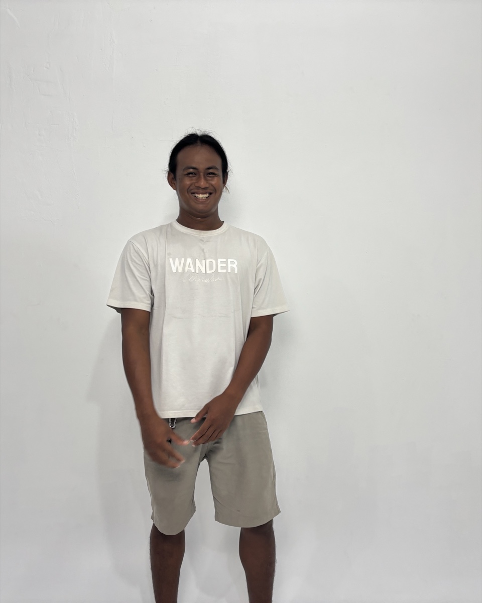 Rifki, smiling, in a white shirt and shorts.
